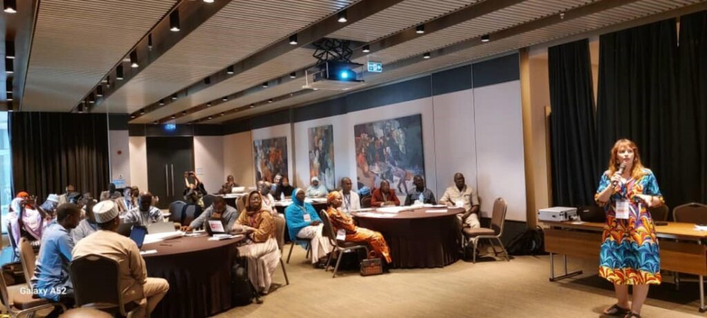 Women standing in front of the training participants and speaking in the microphone.