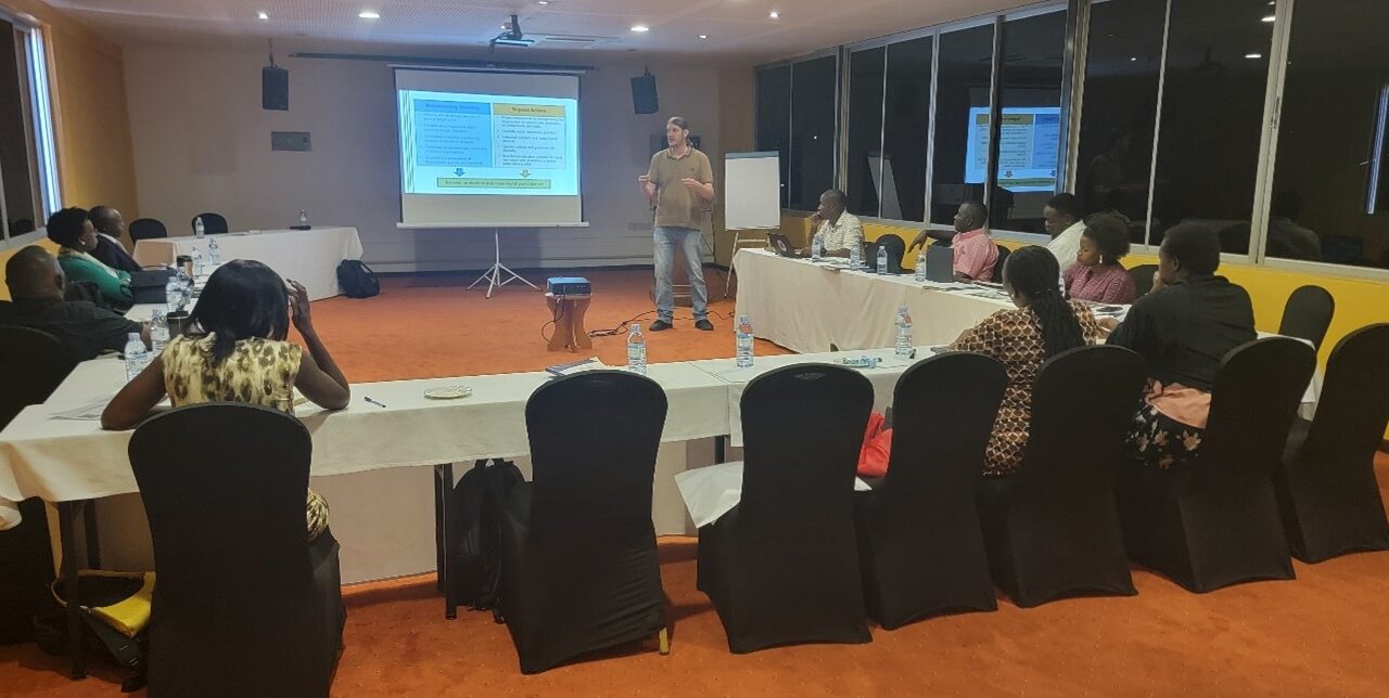 Participant sitting in U-form during training in Kampala. In front facilitator presenting.