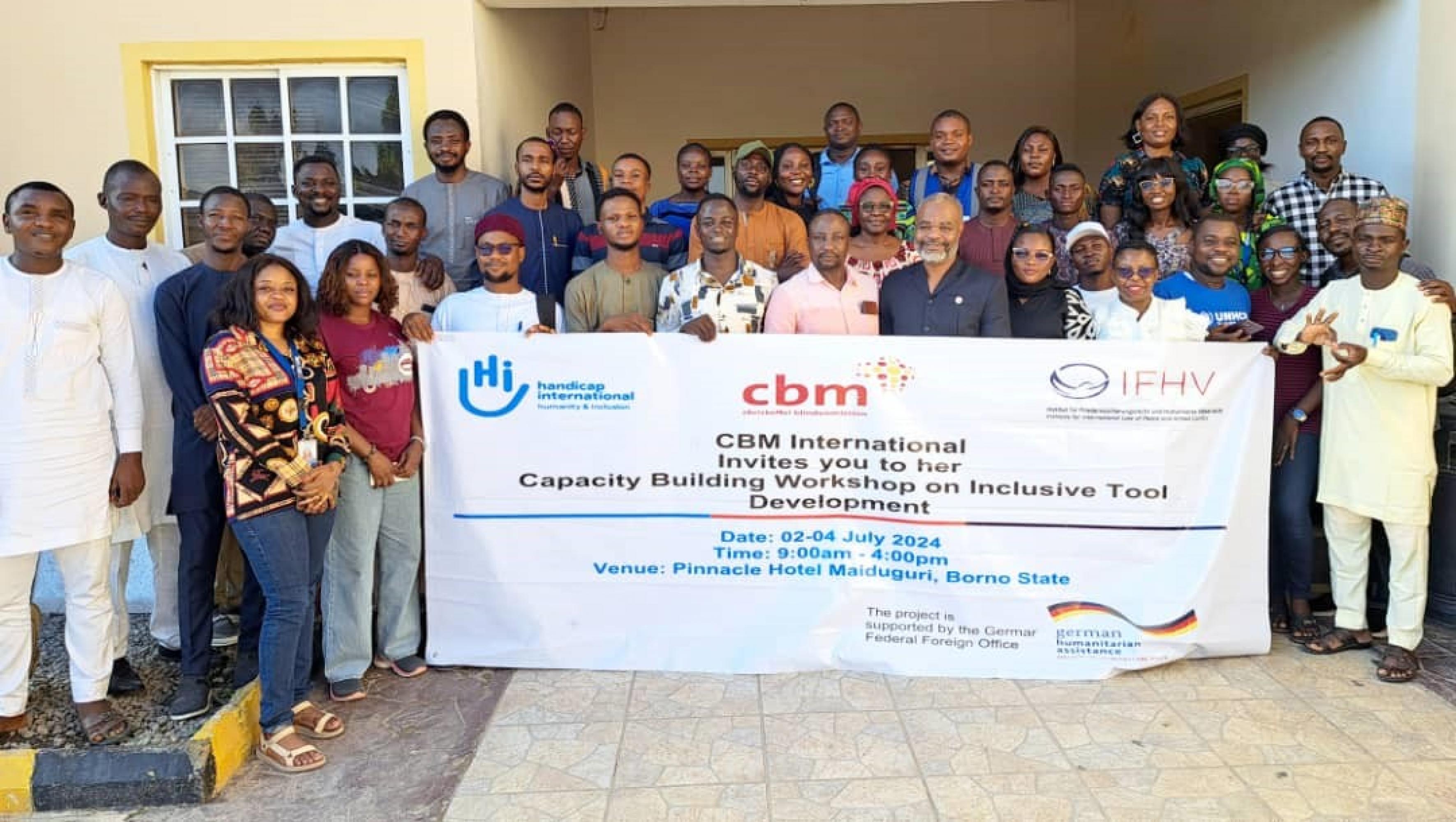 A group of training participants holding a training banner at the entrance of a training venue in Nigeria